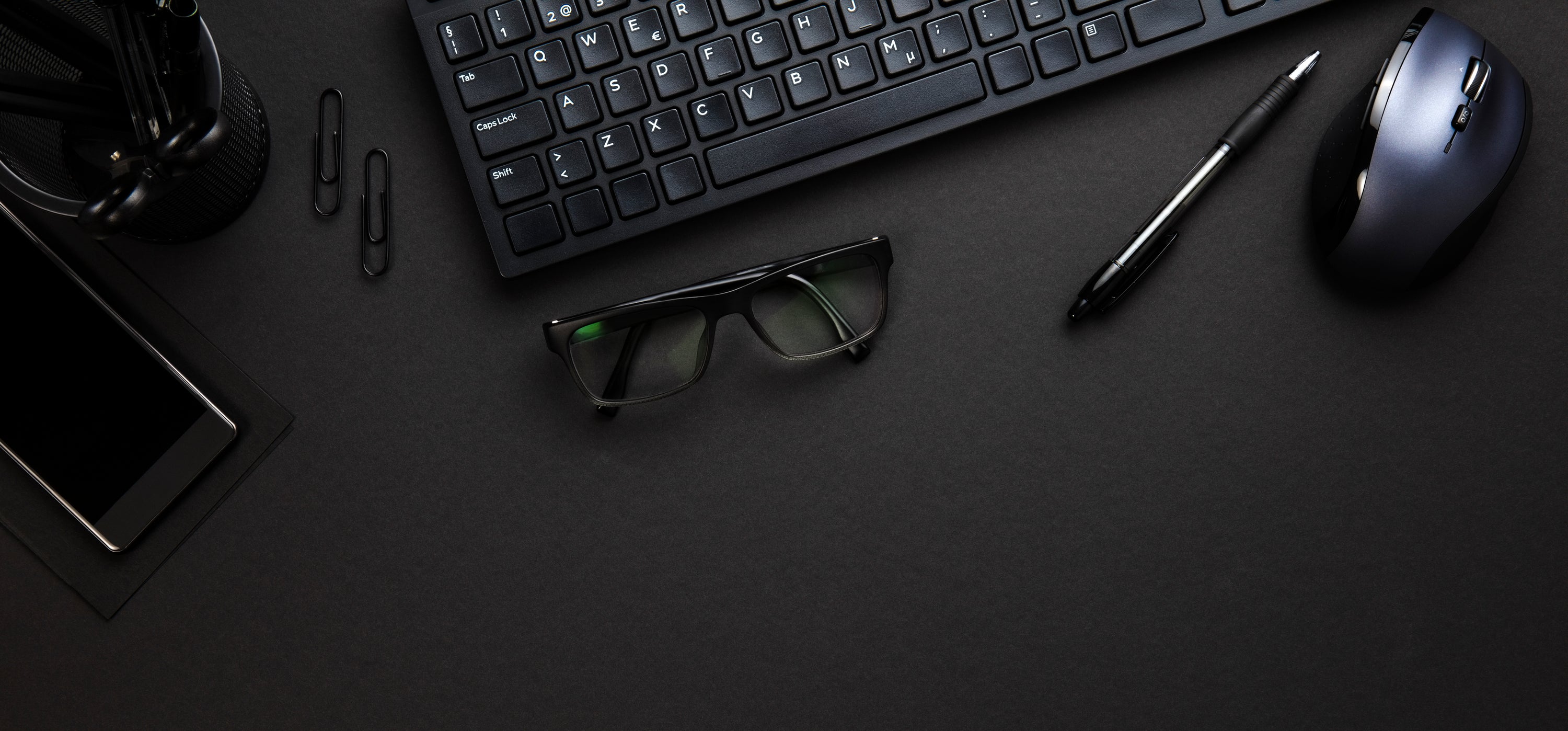 a birds eye view of a desk with a keyboard, mouse, and glasses